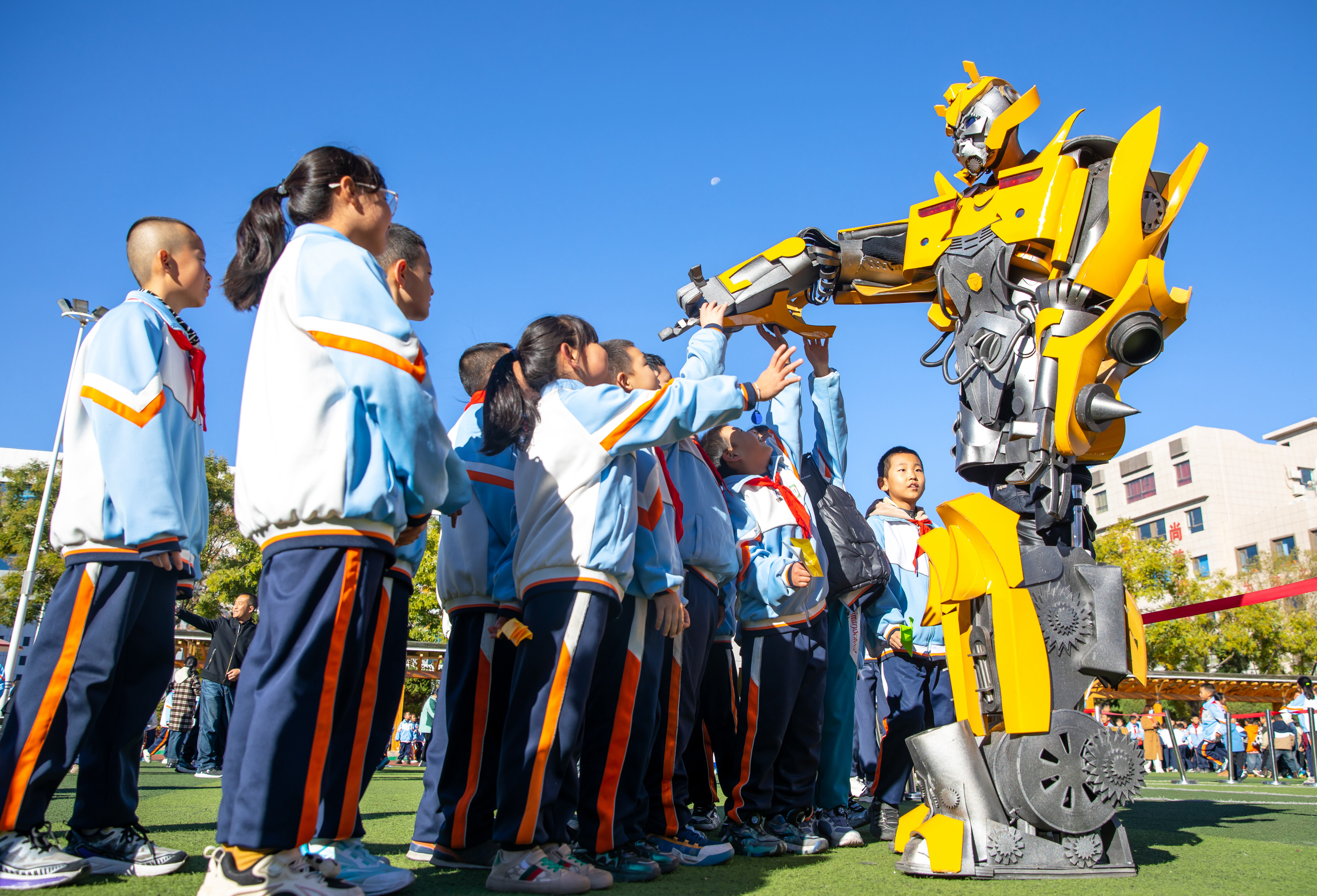 2024年10月22日，在甘肅省張掖市甘州區(qū)北街街小學(xué)科技大篷車嘉年華活動上，學(xué)生與“大黃蜂”機器人互動。楊瀟 攝.jpg