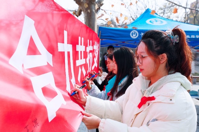 20231127中國石油大學（華東）青年學子在合力共抗艾滋的條幅上簽字，表達抗擊艾滋病的決心和信心  .jpg