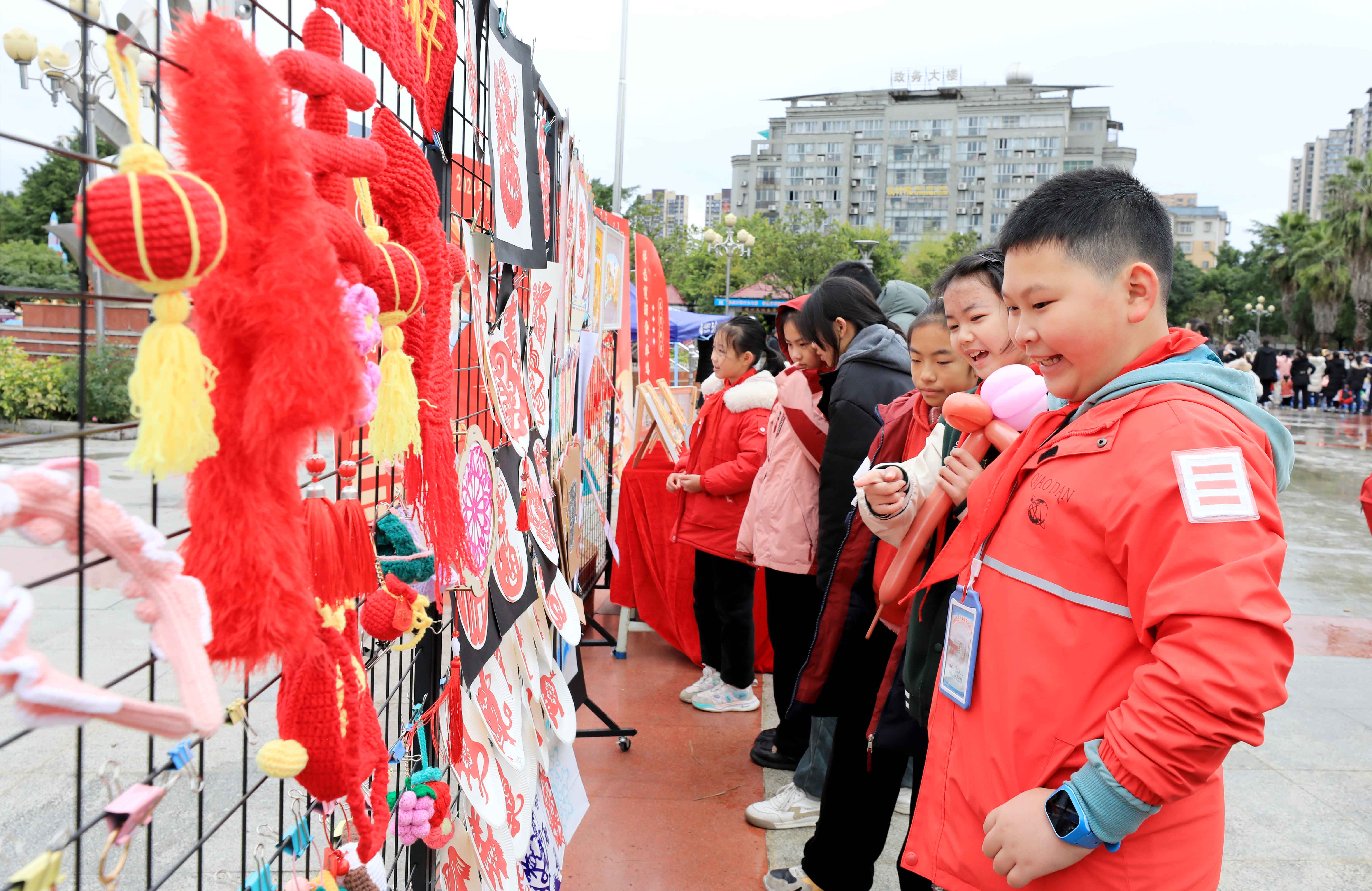 圖7：1月20日，在廣西柳州市融安縣長安廣場，學(xué)生在非遺集市上選購作品。（譚凱興 攝）.JPG