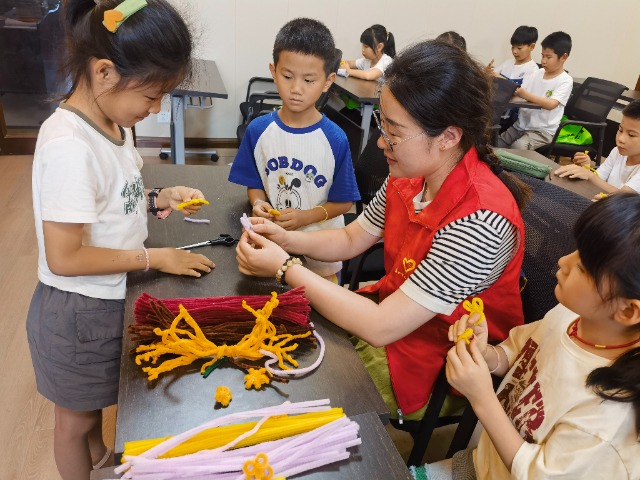 7月12日，在泰州市海陵區(qū)城東街道林湖社區(qū)，泰州市大浦小學(xué)“綠葉”暑期公益班的老師正在教孩子們一起做手工2（拍攝者：泰州市大浦中心小學(xué)  陳惠婷）.jpg